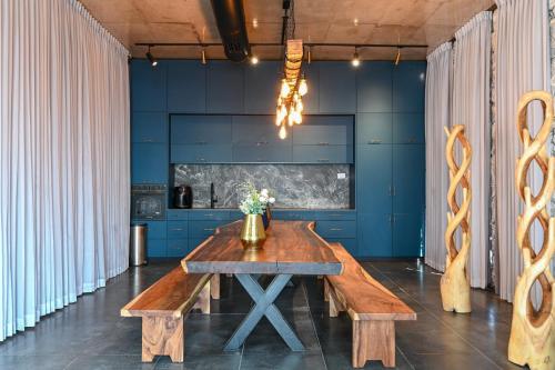 a dining room with a wooden table and benches at הודולה - וילות נדירות עם ממ"ד ובריכות פרטיות ונוף מושלם לכנרת in Giv'at Yo'av