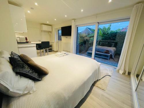 1 dormitorio con cama blanca y ventana grande en Prachtig guesthouse met gratis parkeren, en Maasmechelen