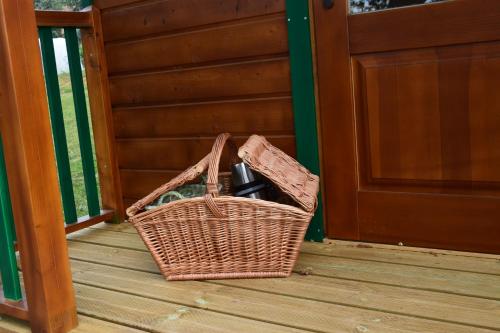 een rieten mand die op een veranda naast een deur staat bij Les Roulottes des Ris in Vallon-en-Sully