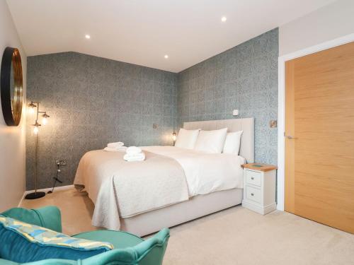 ein Schlafzimmer mit einem großen weißen Bett und einem Stuhl in der Unterkunft Woodbridge Penthouse in Woodbridge