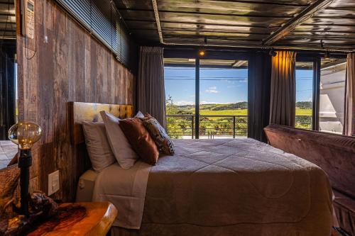 a bedroom with a bed and a large window at Cambará Container in Cambará