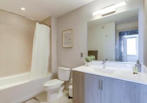 a bathroom with a toilet and a sink and a tub at Fantastic 2BR Condo With Rooftop in Arlington