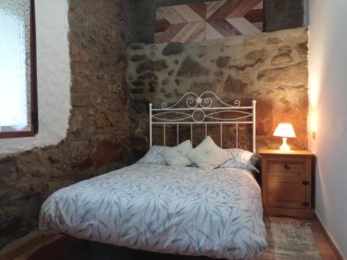 Cama en habitación con pared de piedra en Casa Rural El Turuterro, en Cepeda