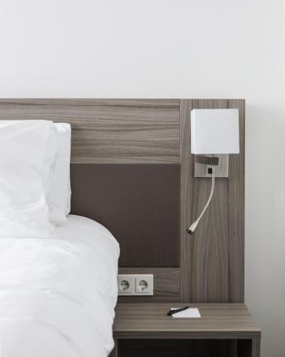 a bed with a night stand with a lamp next to it at Fletcher Hotel-Restaurant Wings-Rotterdam in Rotterdam