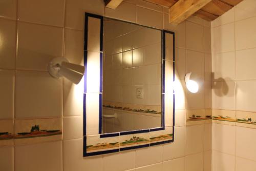 a bathroom with a mirror and a light on a wall at Casa de Viana do Alentejo in Viana do Alentejo