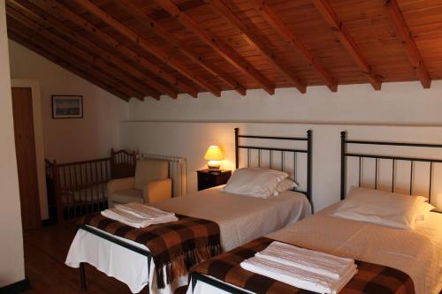 a bedroom with two beds and a chair in a room at Casa de Viana do Alentejo in Viana do Alentejo