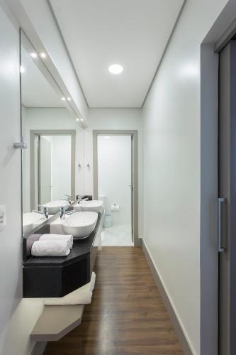 a bathroom with two sinks and two mirrors at Slaviero Blumenau in Blumenau
