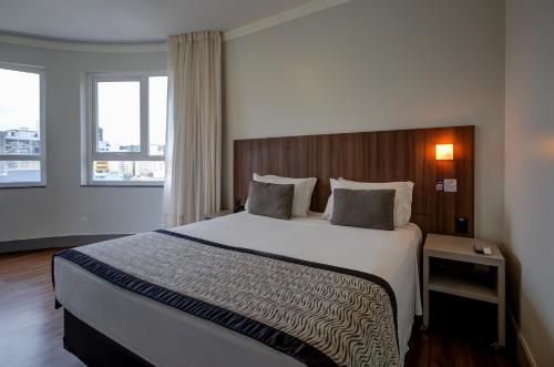 a bedroom with a large bed in a hotel room at Slaviero Blumenau in Blumenau