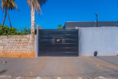 a black garage door with a sign on it at Casa com 2 suítes, cozinha completa , área de lazer, piscina infantil, 10 min do parque aquático in Andradina