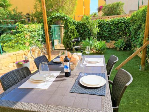 einen Tisch mit Tellern und eine Flasche Wein auf einer Terrasse in der Unterkunft Apartamento con hermoso jardín y AC in Isla Plana