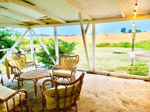 a patio with chairs and tables and a view of a field at Gårdshotellets Camping in Ystad