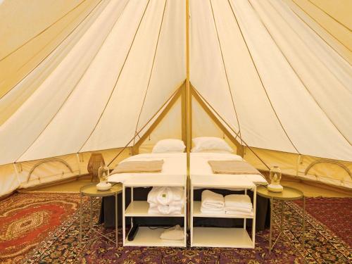 une tente avec un lit et deux tables. dans l'établissement Gårdshotellets Camping, à Ystad