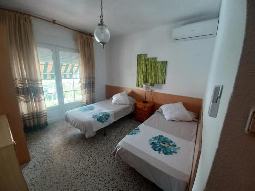 um quarto de hotel com duas camas e uma janela em El Rincón de la Rosa em La Zubia