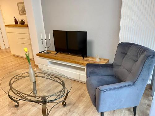 a living room with a blue chair and a television at Haus Maria Isenburg - Naturpark Rhein-Westerwald in Isenburg