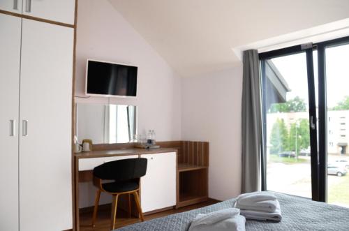 a bedroom with a bed and a desk with a television at Tip Tap Guest House in Druskininkai