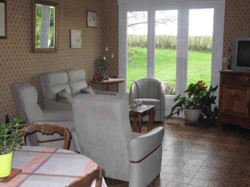 Una sala de estar con un sofá y sillas y un televisor. en Chambres d'hôtes La Pinderie, en Val Couesnon