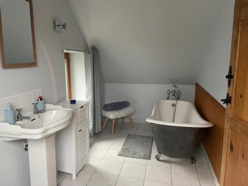 y baño con bañera, 2 lavabos y bañera. en La Bureliere- Holiday home for families, groups and couples, en Gorron