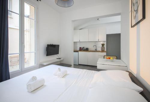 - une chambre blanche avec un grand lit et une cuisine dans l'établissement 5#Studio 2Pers#Paris 15#Commerce#AC, à Paris