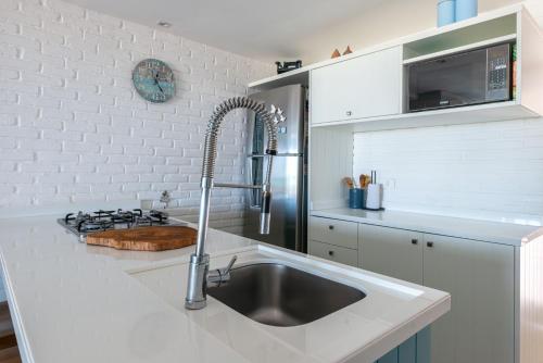 a white kitchen with a sink and a stove at Paraíso a Beira Mar de Porto de Galinhas in Porto De Galinhas