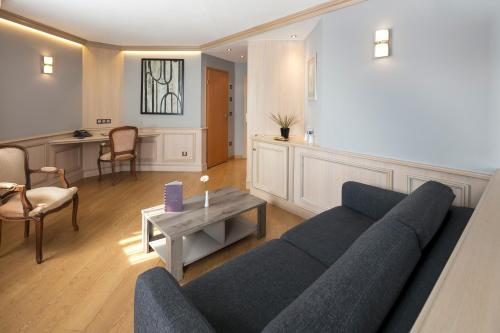 a living room with a blue couch and a table at Cottage Logis Hôtel - Restaurant in Dudelange