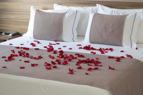 a bed with red rose petals on it at Hotel del Príncipe in Marabá