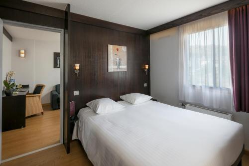 a bedroom with a large white bed and a window at Cottage Logis H&ocirc;tel - Restaurant in Dudelange