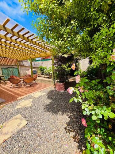 a garden with a wooden pergola and a bench and flowers at Cabaña Algarrobo in Algarrobo