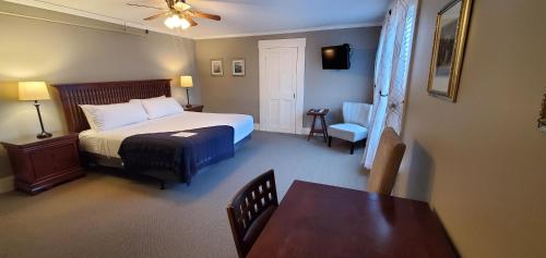 a bedroom with a bed and a table and a chair at The New London Inn in New London