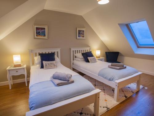 a attic bedroom with two beds and a window at Heatherlea in Carinish