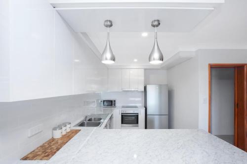 a white kitchen with a large white counter top at 31 Cornwallis Close in Port Macquarie