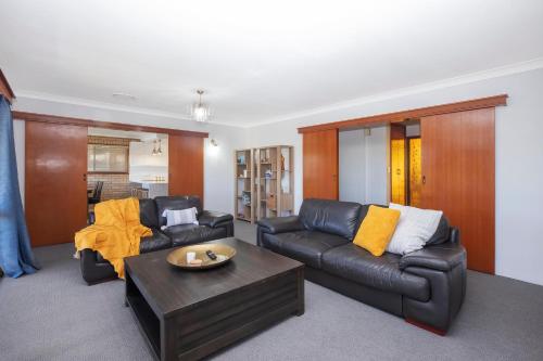 a living room with a leather couch and a coffee table at 31 Cornwallis Close in Port Macquarie