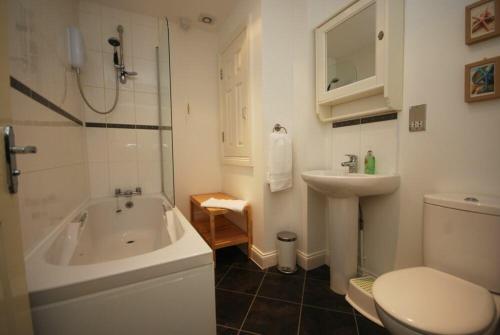 a bathroom with a tub and a toilet and a sink at House Martins Beadnell in Beadnell