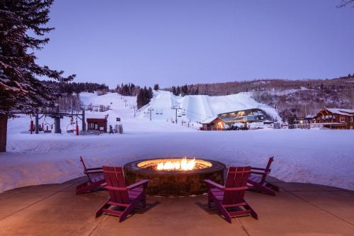 a fire pit with two chairs and a snow covered yard at The Inn at Aspen in Aspen