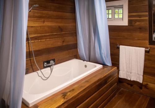 a bath tub in a bathroom with wooden walls at Dolphin Blue Paradise in Bocas Town