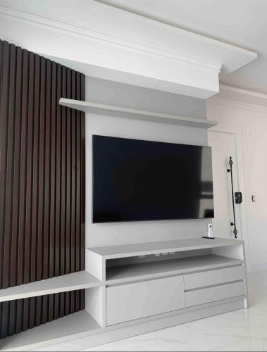 a flat screen tv sitting on top of a white entertainment center at Apartamento 3 suítes 1 quadra do mar in Itapema