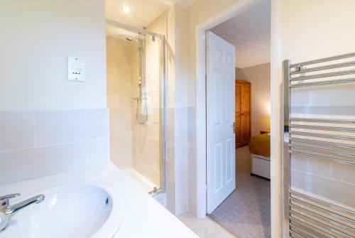 een witte badkamer met een douche en een wastafel bij 4 Bed House in Castle Donington (EMA) with parking in Castle Donington