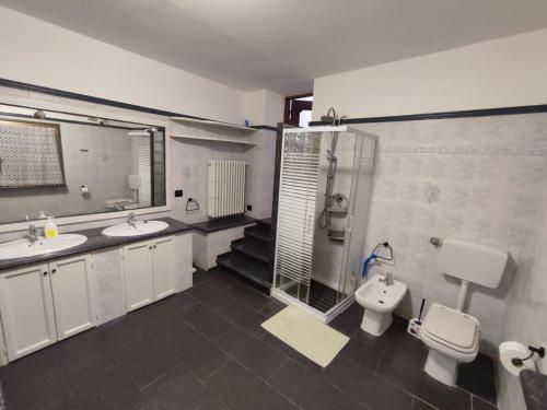 een badkamer met 2 wastafels, een toilet en een douche bij Henson appartamento in Tortona