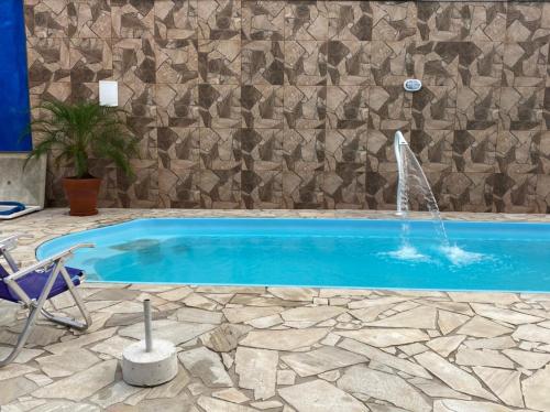 a swimming pool with a fountain in front of a stone wall at Pousada Canto Juquehy in Juquei
