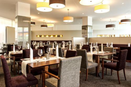 a restaurant with tables and chairs and lights at Mercure Düsseldorf Kaarst in Kaarst