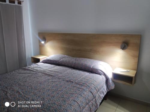 a bedroom with a bed with a wooden headboard at Departamentos Reibel in Colón