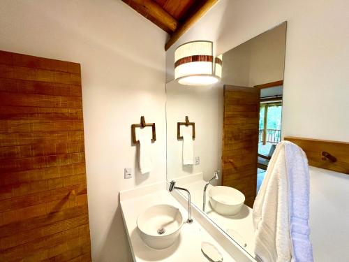 y baño con lavabo, aseo y espejo. en CHALÉ PREGUIÇA TRANCOSO, en Porto Seguro