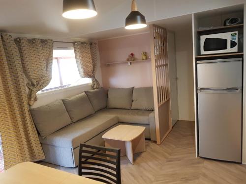 uma pequena sala de estar com um sofá e um frigorífico em Mobil home MAXI CONFORT SUR LA COTE D'AZUR em Fréjus