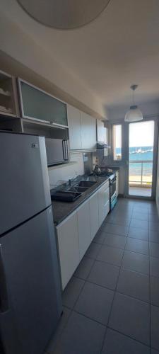 a kitchen with white appliances and a large window at Mirador del Golfo Puerto Madryn in Puerto Madryn