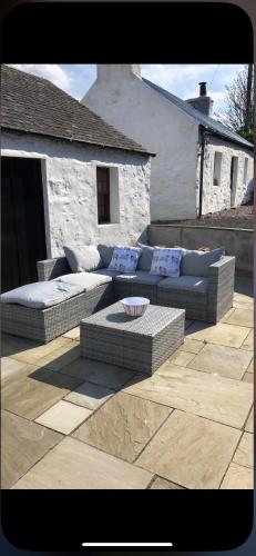 a patio with couches and a table and a building at Old Tynribbie House - Comfortable Detached House in Appin