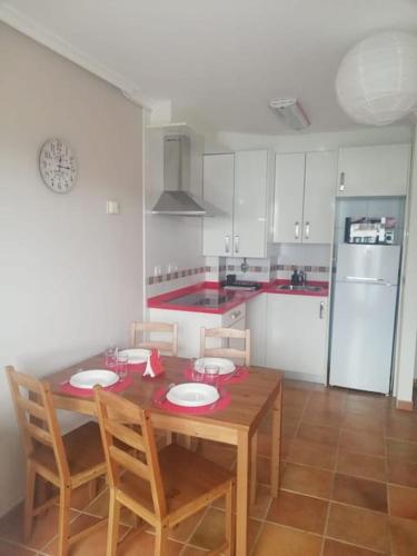 a kitchen with a wooden table with two chairs and a kitchen with a refrigerator at Apartamento Colombres in Colombres