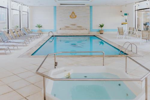 a large swimming pool in a room with chairs and a tub at Hotel Minas Gerais in Poços de Caldas