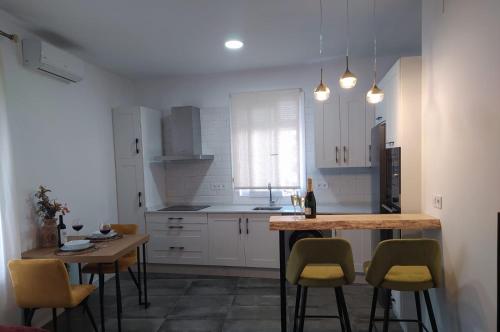 Loft Casa del Agua Ubrique في أوبريق: مطبخ مع دواليب بيضاء وطاولة وكراسي