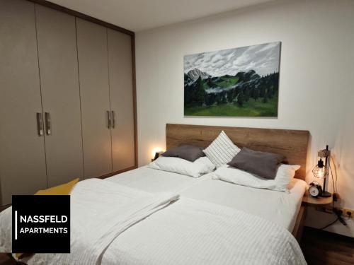 a bedroom with a large bed with white sheets and pillows at Haus Anja NASSFELD APARTMENTS in Sonnenalpe Nassfeld