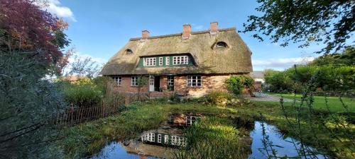 an old stone house with a reflection in a pond at "Haus auf dem Berg" in Westensee