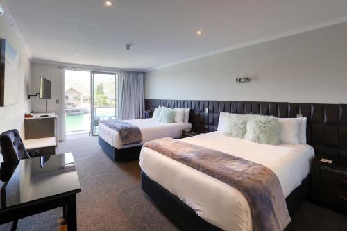 a hotel room with two beds and a television at Marsden Lake Resort Central Otago in Cromwell